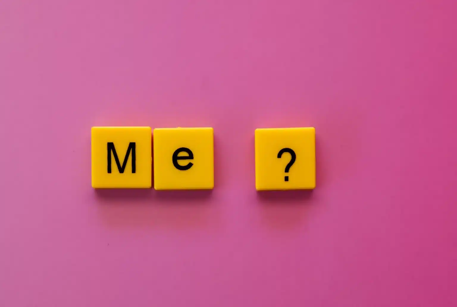 Yellow letter tiles spelling Me with a question mark on a pink background