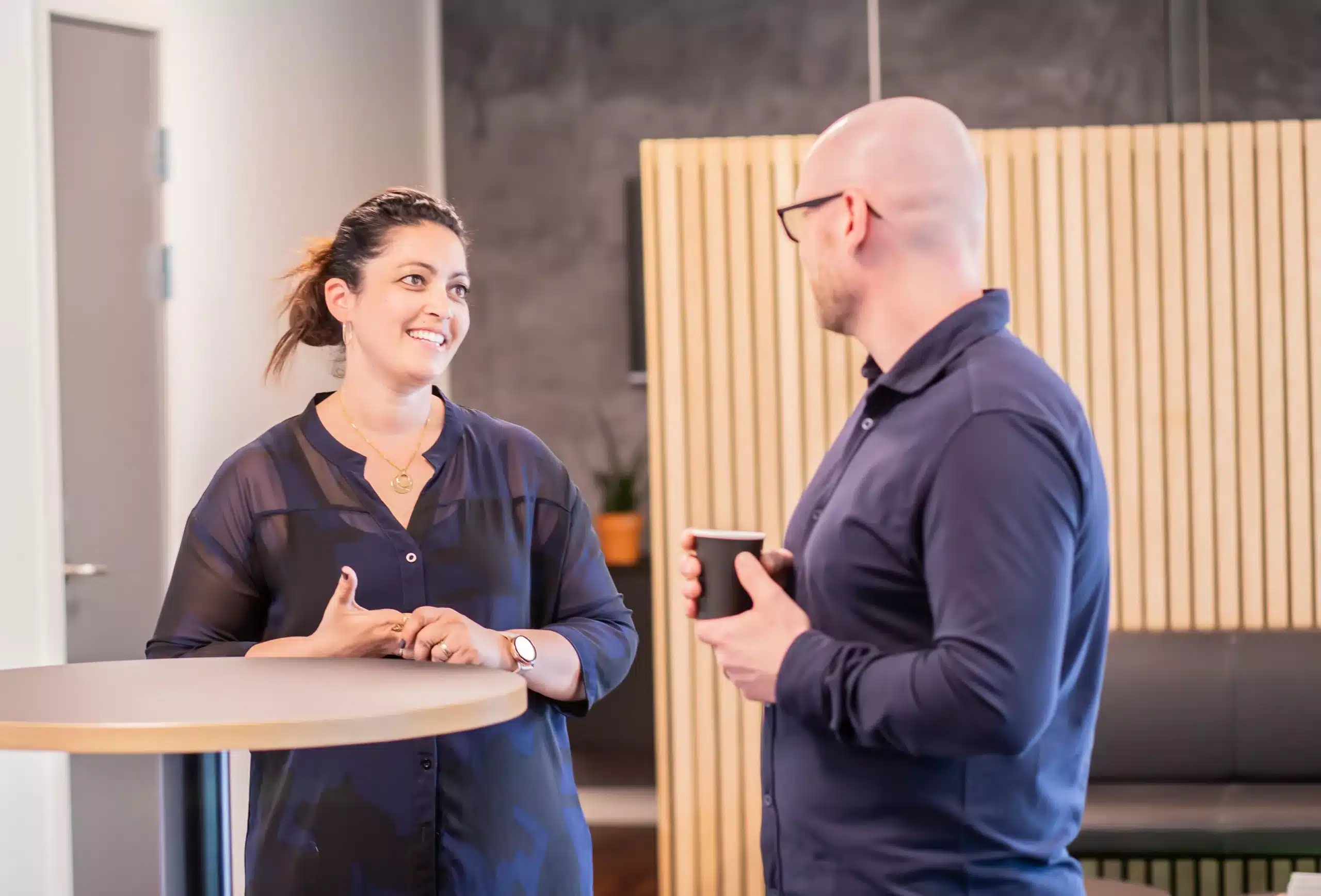 Two colleagues talking at a standing table in a bright office