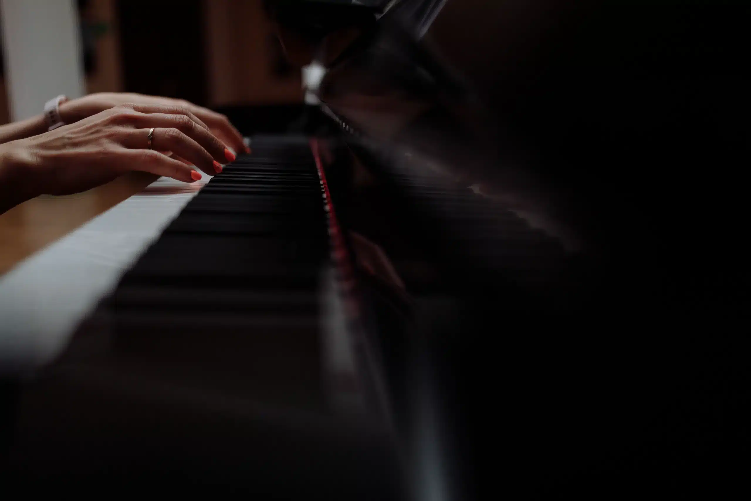 Hands playing a grand piano in a warmly lit room