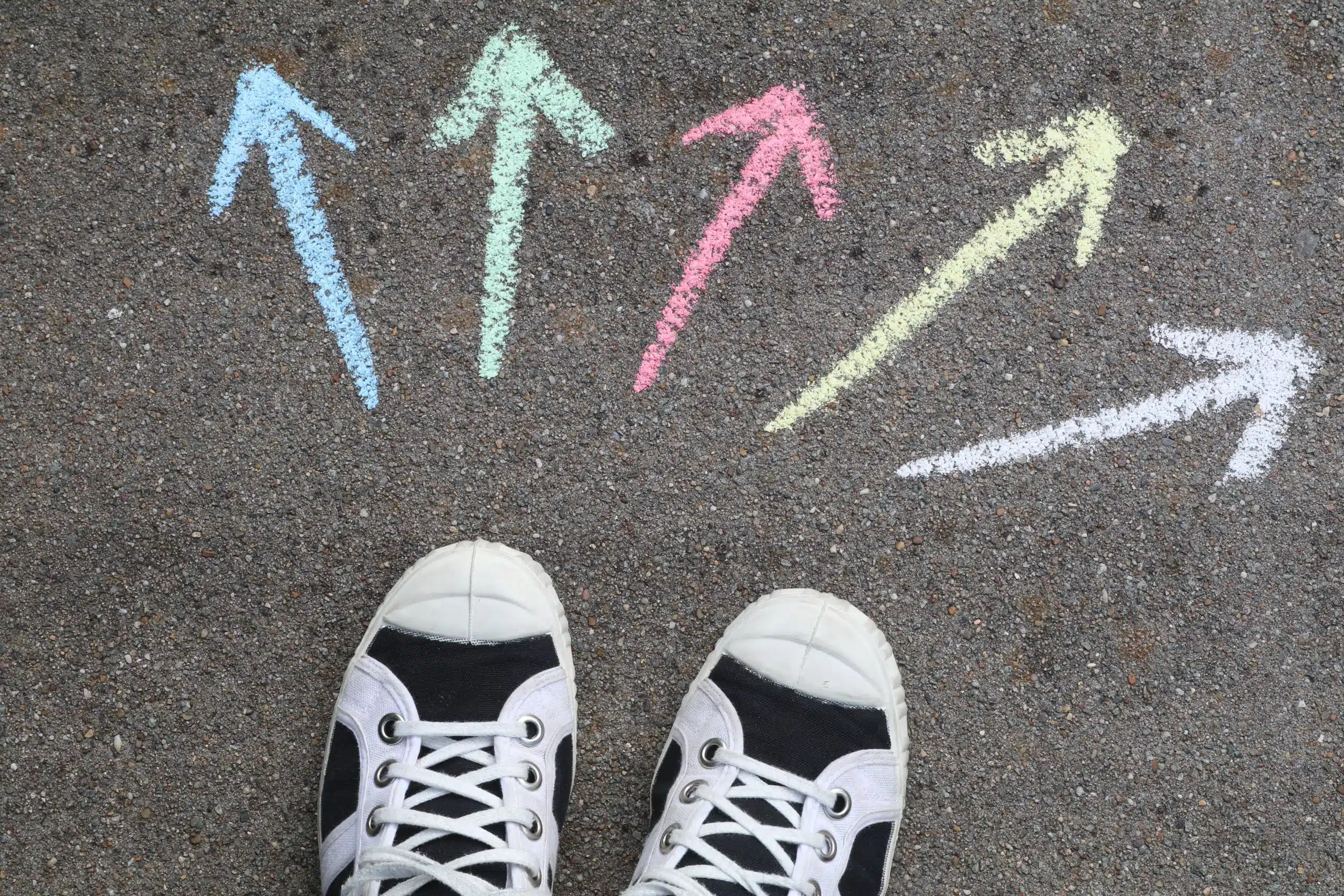 Trainers facing colourful chalk arrows pointing in different directions